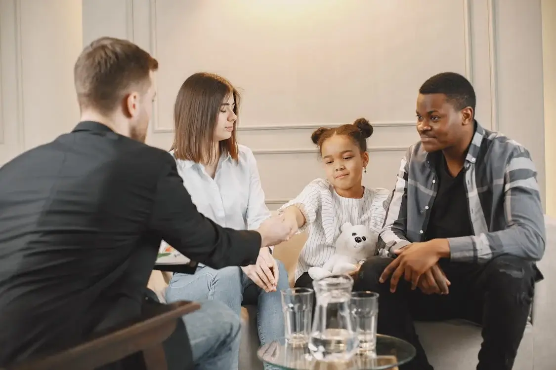 man, woman, and their daughter seated across from their therapist man, woman, and their daughter seated across from their therapist
