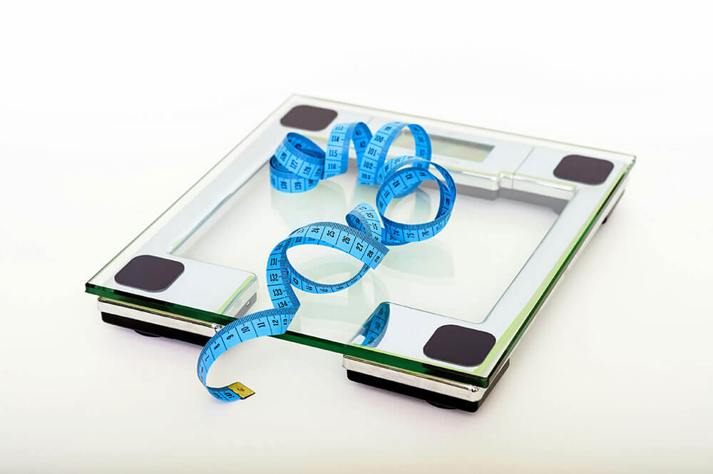 scale-diet-fat-health weight loss concept image - tape measure on top of digital bodyweight scale