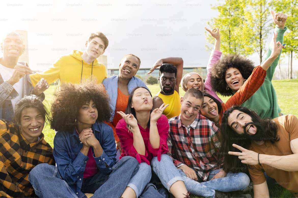 A group of culturally diverse people smiling, and posing for a picture outside